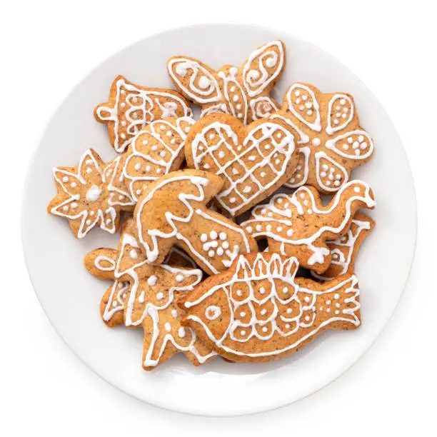 Many Decorated Christmas gingerbread cookies on a white ceramic plate isolated on white. Top view.
