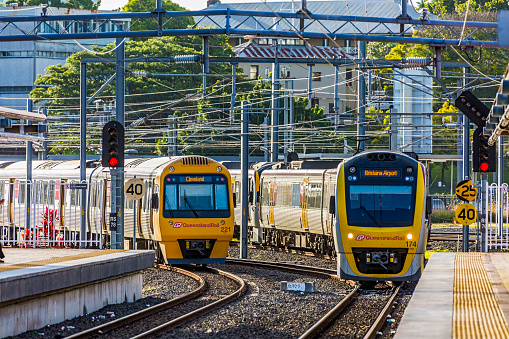 Brisbane, Australia - Nov 20, 2017:  A Queensland Rail peak hour service to Brisbane Airport arrives at Brisbane's Roma Street Station as a service to suburban Cleveland departs. Electric commuter trains passing under maze of electric overhead wires.