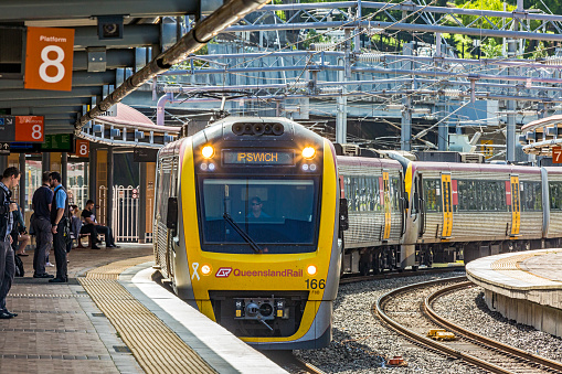 Brisbane, Australia - Nov 20, 2017:  A Queensland Rail peak hour service to Ipswich arrives at Brisbane's Roma Street Station Platform 8. Electric commuter train, curved railway station platform.