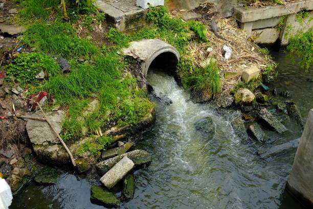 águas residuais fluem do esgoto para o canal, conceito de degradação ambiental. - águas residuais - fotografias e filmes do acervo