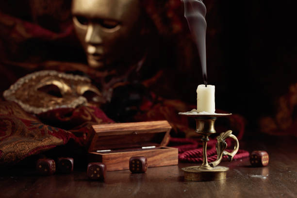 istock Extinguished candle, dice, and carnival masks on an old wooden table. 1442174012