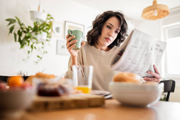 Young woman reading newspaper at home stock photo
