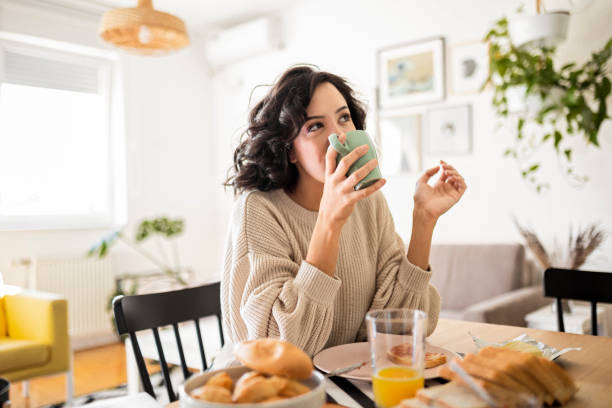 집에서 커피를 마시는 젊은 여자 - waffle breakfast food sweet food 뉴스 사진 이미지