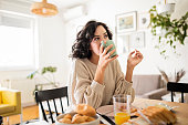 Young woman having breakfast at home drinking coffee