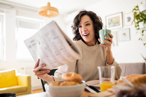 istock Young woman having coffee after breakfast at home while reading newspaper 1442177786