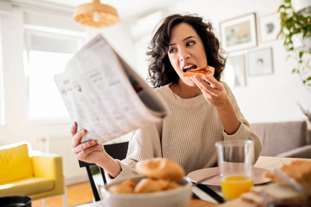 istock Young woman having breakfast at home reading newspaper 1442177969