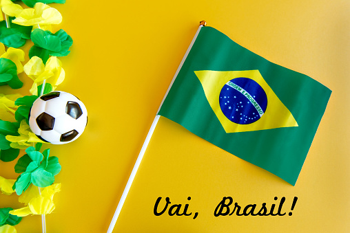 Soccer ball and Brazilian flag on yellow background.