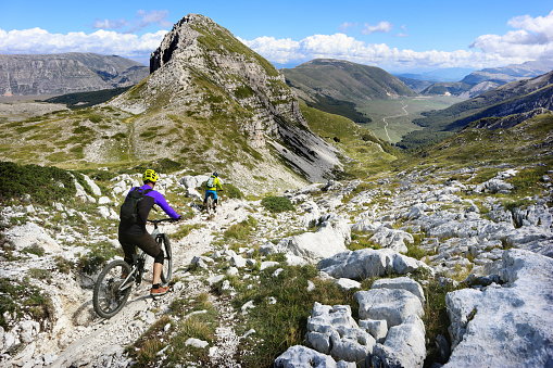 Three mountain bikers descending from Rifugio Sebastiani towards Piani di Pezza, in the Velino Sirente Park, in Abruzzo
