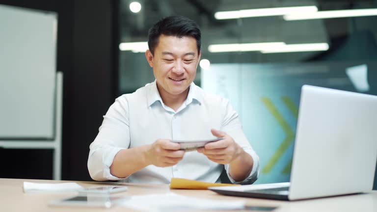 Happy asian man employee counting savings cash dollars in the office Business man banker takes out counts banknotes financial salary bribe