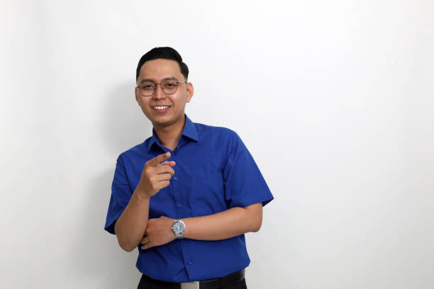istock Happy young asian employee standing while pointing and looking at the camera. Isolated on white background 1442183993