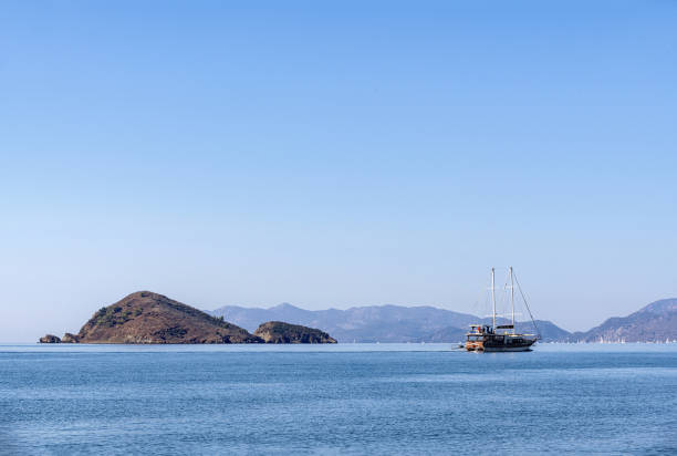A sailing tour boat at sea in Fethiye, Turkey and a small rocky island in the background.