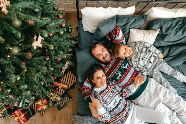 Happy family near fir-tree in bedroom, Christmas celebration at home close up