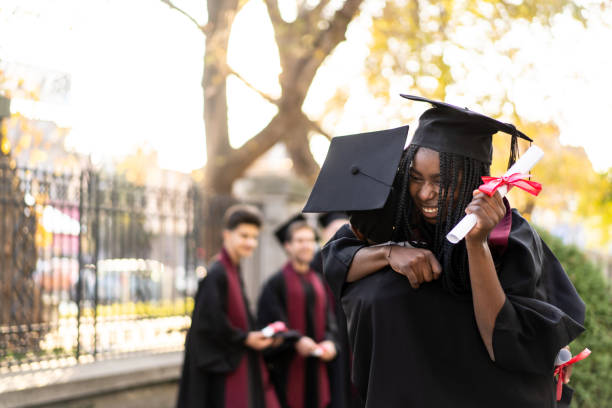 Young student is embracing each other after the graduating ceremony stock photo