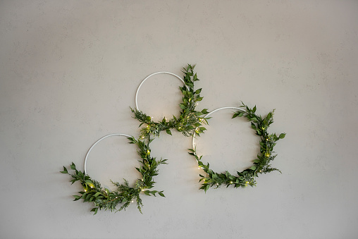 On gray concrete wall, there are three laconic, elegant, green wreaths made from natural materials.