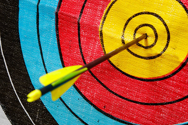 A close-up of an arrow on the center of a colorful target stock photo