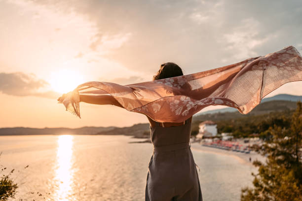 istock Young Woman Spreading Her Arms While Holding A Scarf At The Beach 1442190573