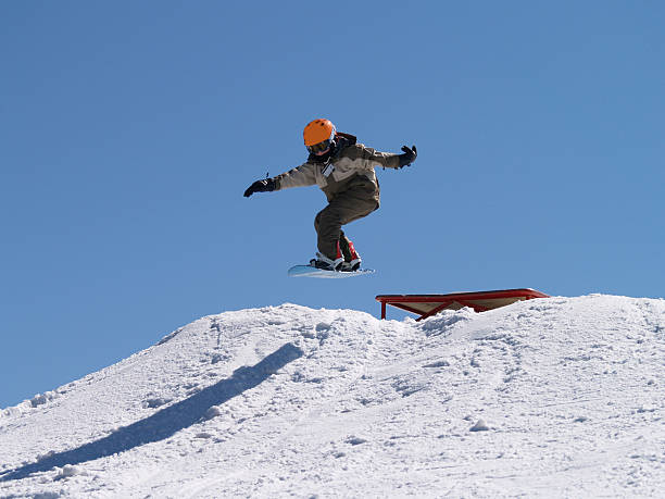istock Snowboarder Jumps off Grinding Rails 144219063