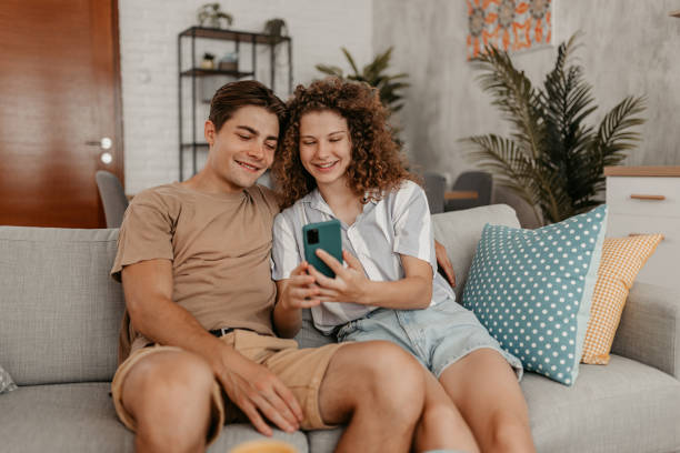 istock Young Couple Sitting On The Sofa And Sharing Social Media Feeds 1442193227