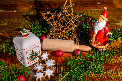 Christmas scene with cinnamon stars, Santa Claus, rolling pin, a ceramic biscuit tin and other christmas decoration.