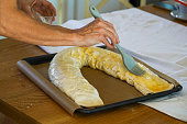 Butter and egg spread is added to the rolled up, apple strudel in baking pan