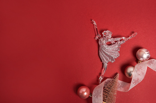 Decoration for Christmas, a small figurine of a ballerina with pink balls on red background, greeting card with copy space