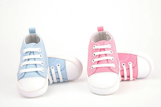 Two pairs of baby shoes, one pair blue and one pair pink stock photo
