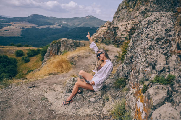 istock Young woman freelancer traveler working online anywhere outdoors using laptop enjoying mountain peak view. Happy female downshifter in sunglasses holding computer in unusual workplace at summer. 1442200458