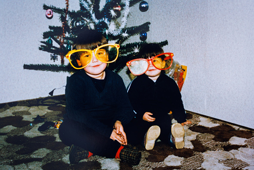 istock Brother and sister next to Christmas tree with funny eyeglasses looking at camera 1442204988