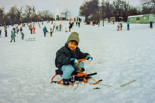 Little boy sitting on vintage sled at the eighties