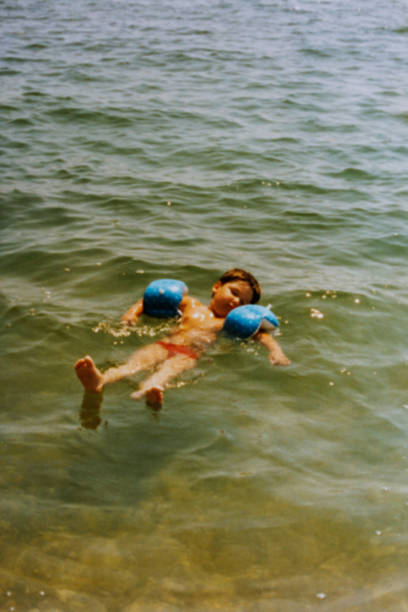 garotinho achatando no mar durante o verão dos anos oitenta - child swimming pool swimming little boys - fotografias e filmes do acervo
