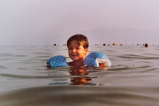 Chubby little boy swimming in sea at eighties