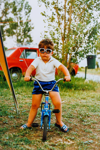istock Funny little boy sitting on bicycle at eighties 1442205314