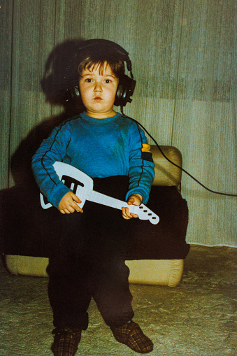 Little chubby boy playing guitar toy at eighties