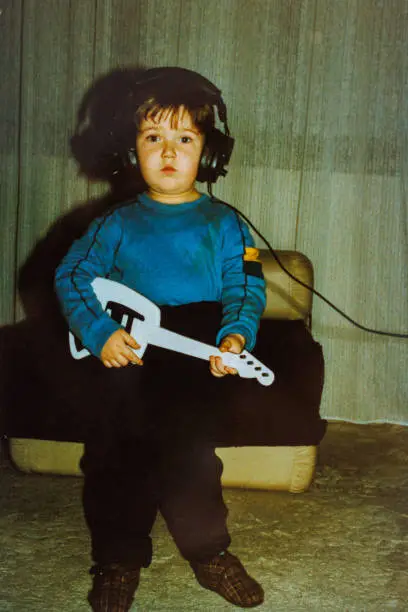 Photo of Little chubby boy playing guitar toy at eighties