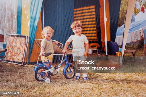 istock Brother and sister posing by bicycle in camp at eighties 1442205471