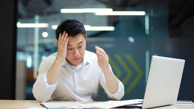 Upset asian employee getting bad results of project in office Frustrated business man finding mistakes fail in documents paperwork failure at workplace