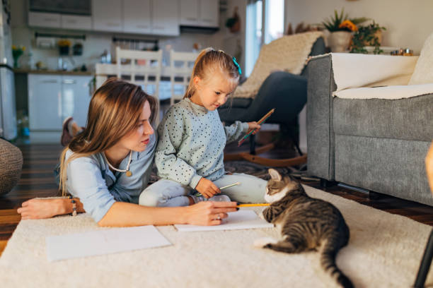 istock Mother and her daughter draw on white papers, while their cat wants to play with them 1442207349