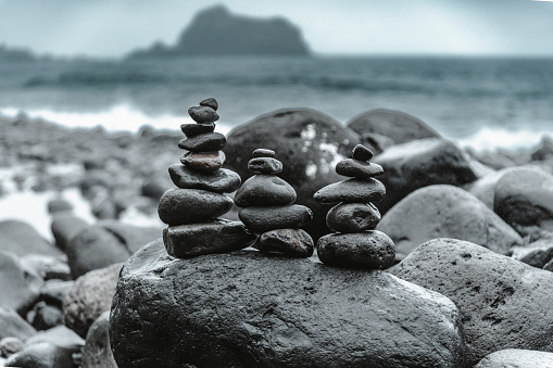 Balancing stones on the beach in Ribeira da Janela, Madeira island, Portugal.