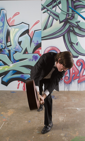 Man in a tux smashing a small guitar or ukulele. - see lightbox for more