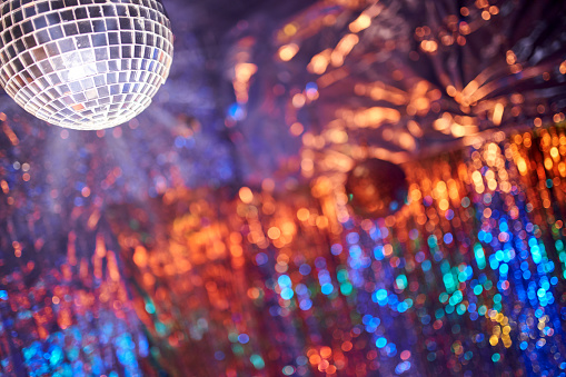 Mirror disco ball on shiny background with bokeh lights. Holiday abstract image with defocused lights. Copy space