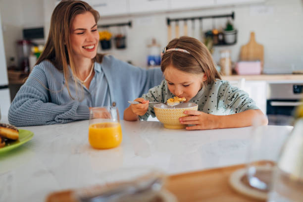 istock A mother looks after her daughter while the girl eats cereal for breakfast 1442209901