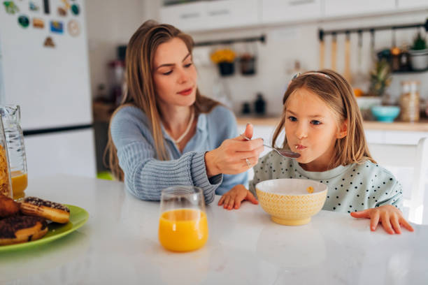 istock A young mother feeds her daughter while sitting at the dining table 1442210133