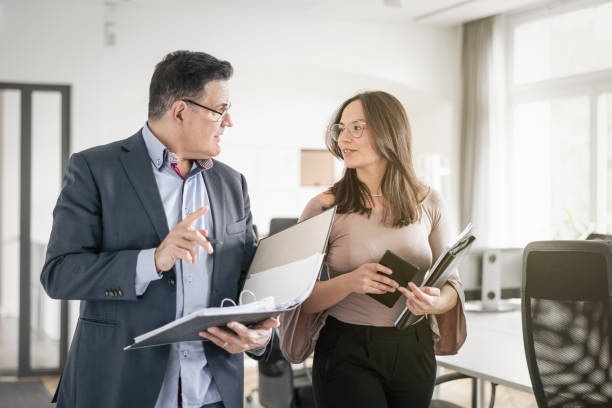 istock Businesspeople discussing over file at while walking in office 1442210271