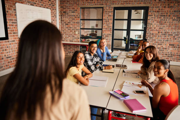istock Smiling students listening to their teacher talking in a classroom 1442210273