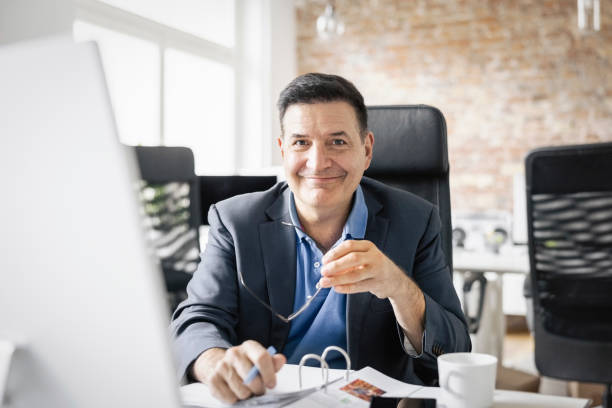 Portrait of a happy mid adult businessman sitting at office stock photo