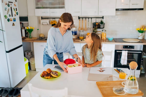 Mother and her daughter are having crazy fun while packing lunch in a lunch box