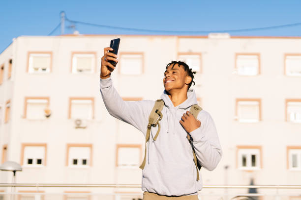 istock Cheerful young man using cell phone in the city on sunny day 1442212453