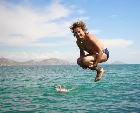Jumping happy man over water