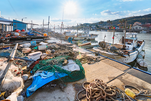kyushu, fukuoka - december 08 2021: A bunch of Japanese fisherman's equipments like nets, ropes and buoys on the pier of the Tsuyazaki fishing port with fishing boats moored in the city of Fukutsu.