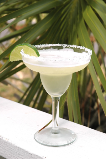 Margarita with salt and lime with palm tree in background.